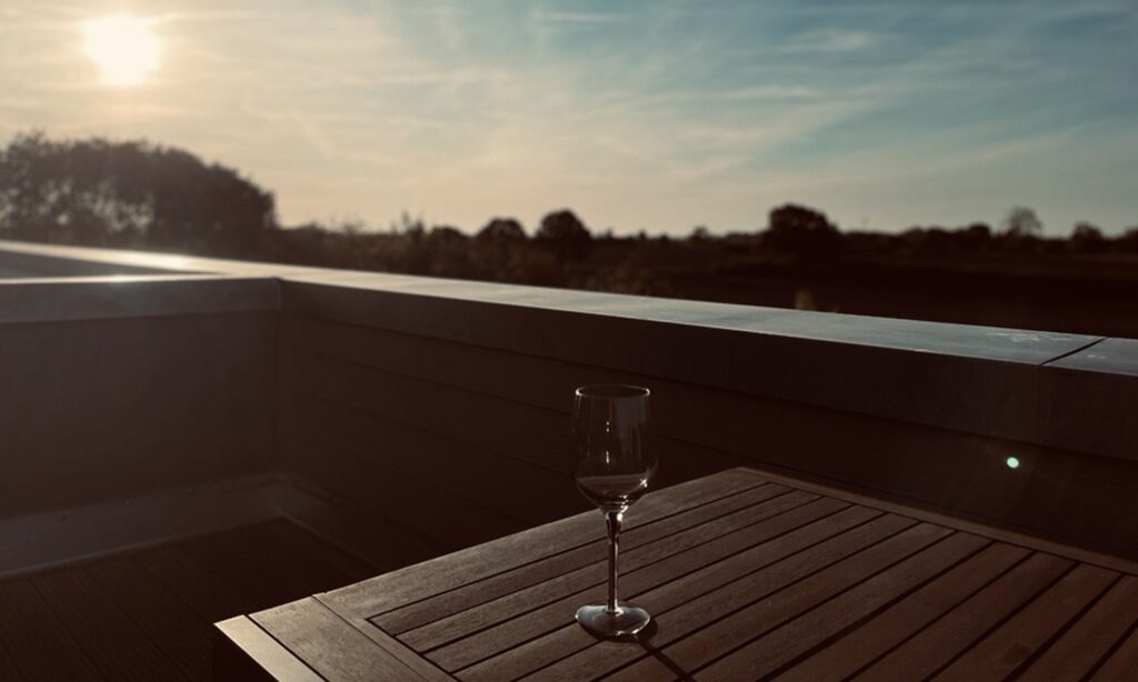 Weinglas auf dem Terrassentisch bei Sonnenuntergang